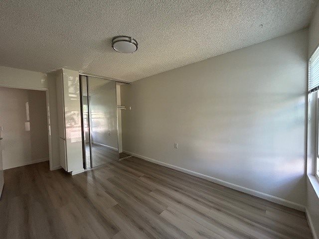 A room with a sliding glass door and wood flooring.